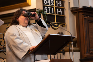 Mit einem Fernglas blickt Diakonin Elisabeth Krauß symbolisch auf 500 Jahre bewegte Vergangenheit ihrer Kirchengemeinde mit Krieg und Frieden, Freud und Leid: „Sie ließen sich nicht unterkriegen, wussten sich getragen von Gott und lobten ihn aus vollem Herzen.“